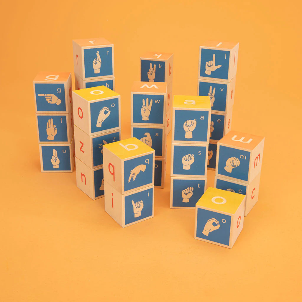 A set of 28 sign language blocks in various colors, each with a different sign language symbol on two debossed sides, arranged on an orange background.