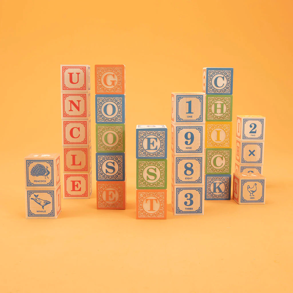 A set of colorful wooden blocks with letters, numbers, and symbols printed on them, arranged in a variety of configurations on an orange background.