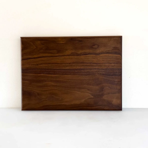 A rectangular dark brown wooden board with prominent natural wood grain patterns, displayed against a plain white background.