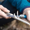 Person using a kids knife to cut stick with a blurred background