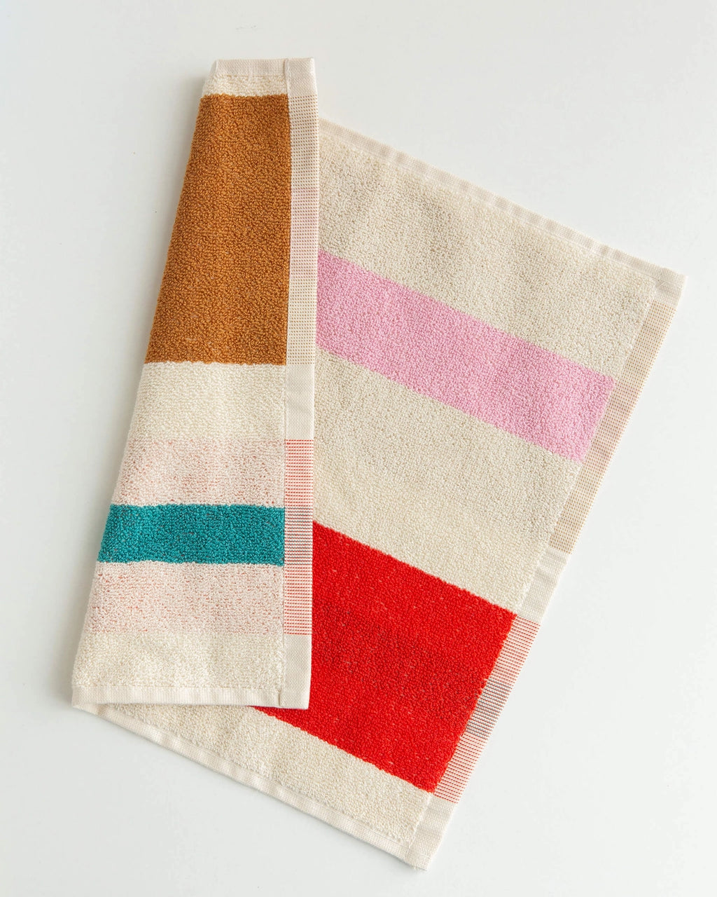 A folded cotton towel with a striped pattern in cream, pink, red, teal, and brown, displayed on a clean white background.