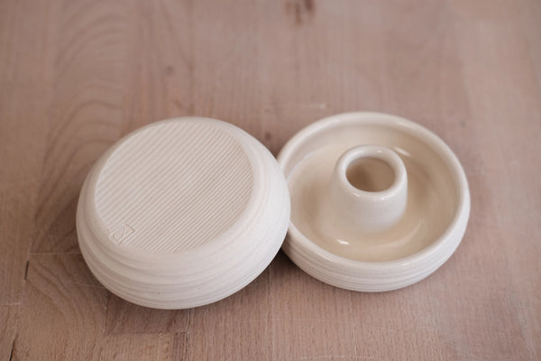 Two white ceramic candle holders on a wooden surface