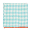 A square napkin with a light blue gingham check pattern and a solid orange-red fringed border.