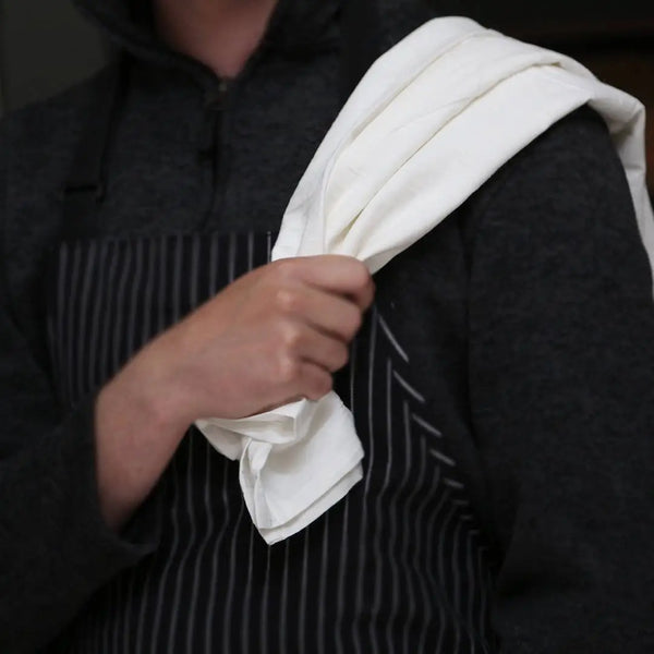 Person holding a white towel over their shoulder with a dark background