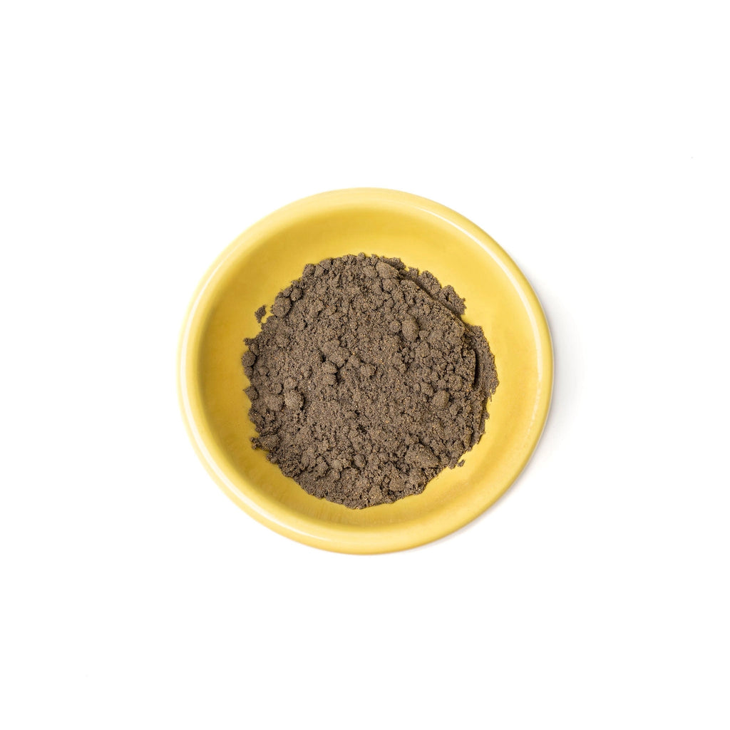Yellow bowl filled with dark brown powder on a white background