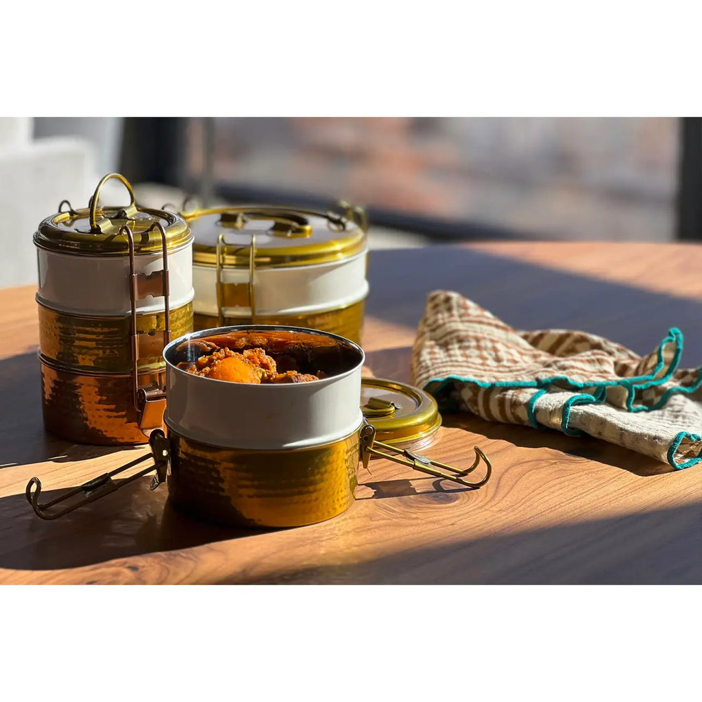 Metal food containers with food on a wooden surface outdoors