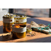 Metal food containers with food on a wooden surface outdoors