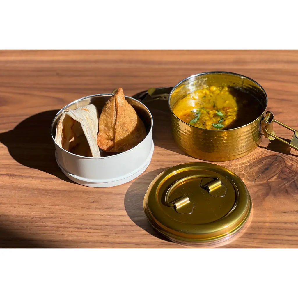 Two metal containers with food on a wooden surface
