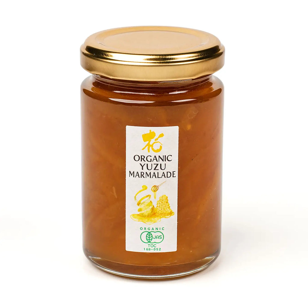 Jar of organic yuzu marmalade with a gold lid on a white background