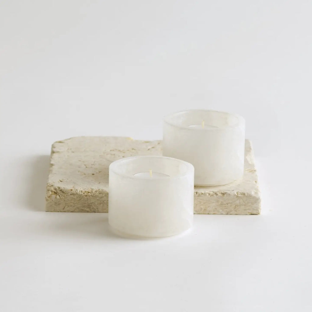 Two white bowls on a light beige stone surface with a plain white background