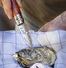 Oyster knife being used on an oyster with a checkered cloth background