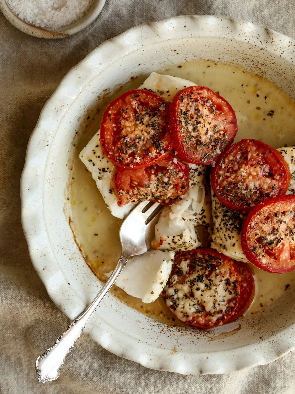Plated dish with cod and tomatoes on a rustic background