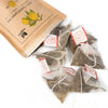Tea bags with red labels and a cardboard bag on a white background