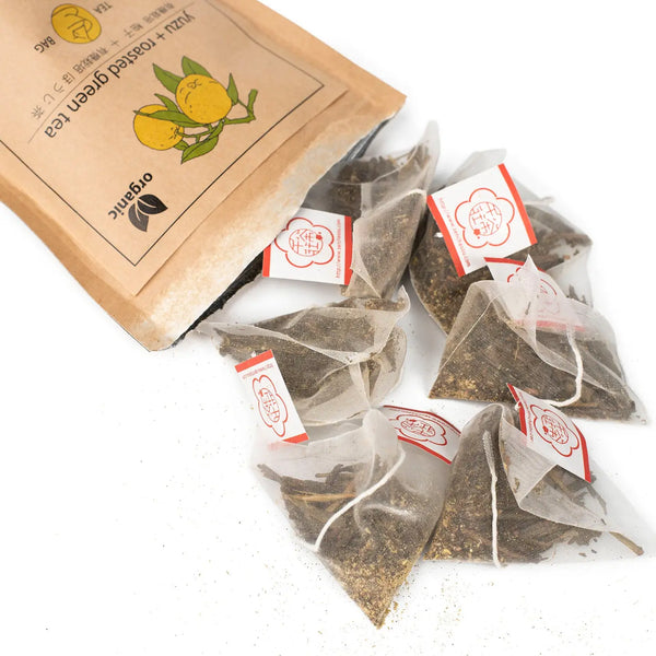 Tea bags with red labels and a cardboard bag on a white background