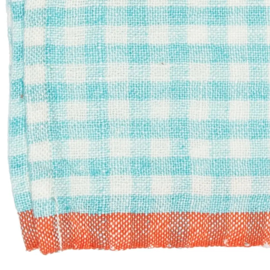 A close-up of a woven napkin with a light blue and white gingham check pattern and a solid orange-red fringed border along the bottom edge.