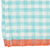 A close-up of a woven napkin with a light blue and white gingham check pattern and a solid orange-red fringed border along the bottom edge.