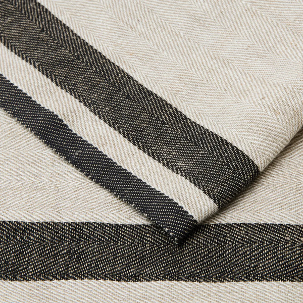 A close-up of a woven textile with a cream base and bold black horizontal stripes, showing the fabric texture and fold detail.