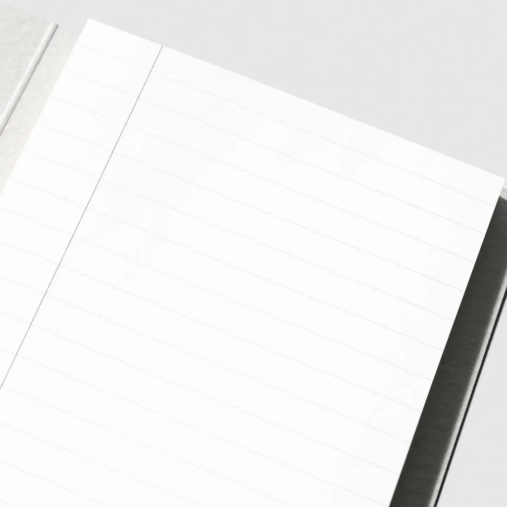 A close-up of a white lined notepad or notebook page with a single vertical ruling, photographed on a light gray background.