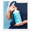 Person holding a bottle of Kerzon giga douz laundry soap against a blue background