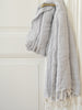 Gray textured towel draped over a wooden hanger against a white wall.