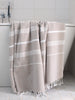 Beige towel with white stripes draped over a bathtub in a bathroom setting.