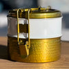 Gold and white container with a lid on a wooden surface