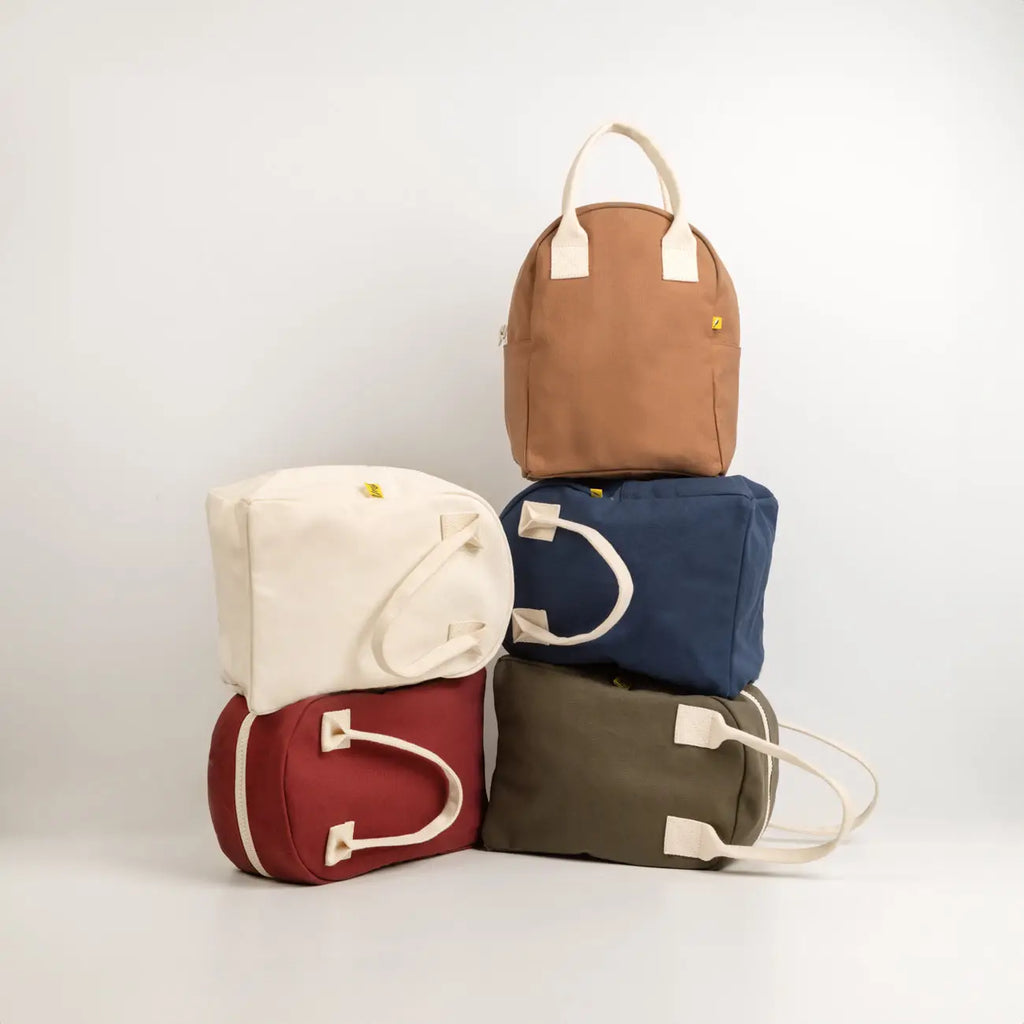 Five fabric bags in different colors stacked on a white background