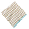 Folded checkered napkin with beige and white pattern and blue border on a white background
