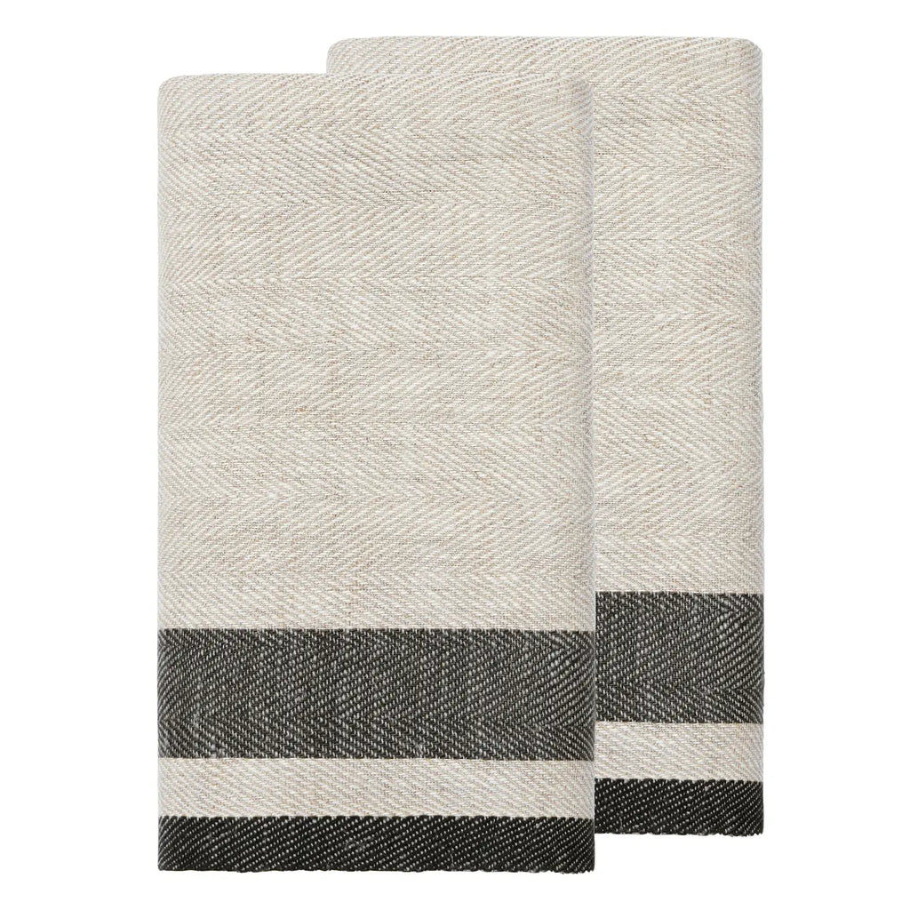 Two folded woven towels in a light oatmeal beige color with a dark charcoal gray and white striped border, displayed on a solid white background.