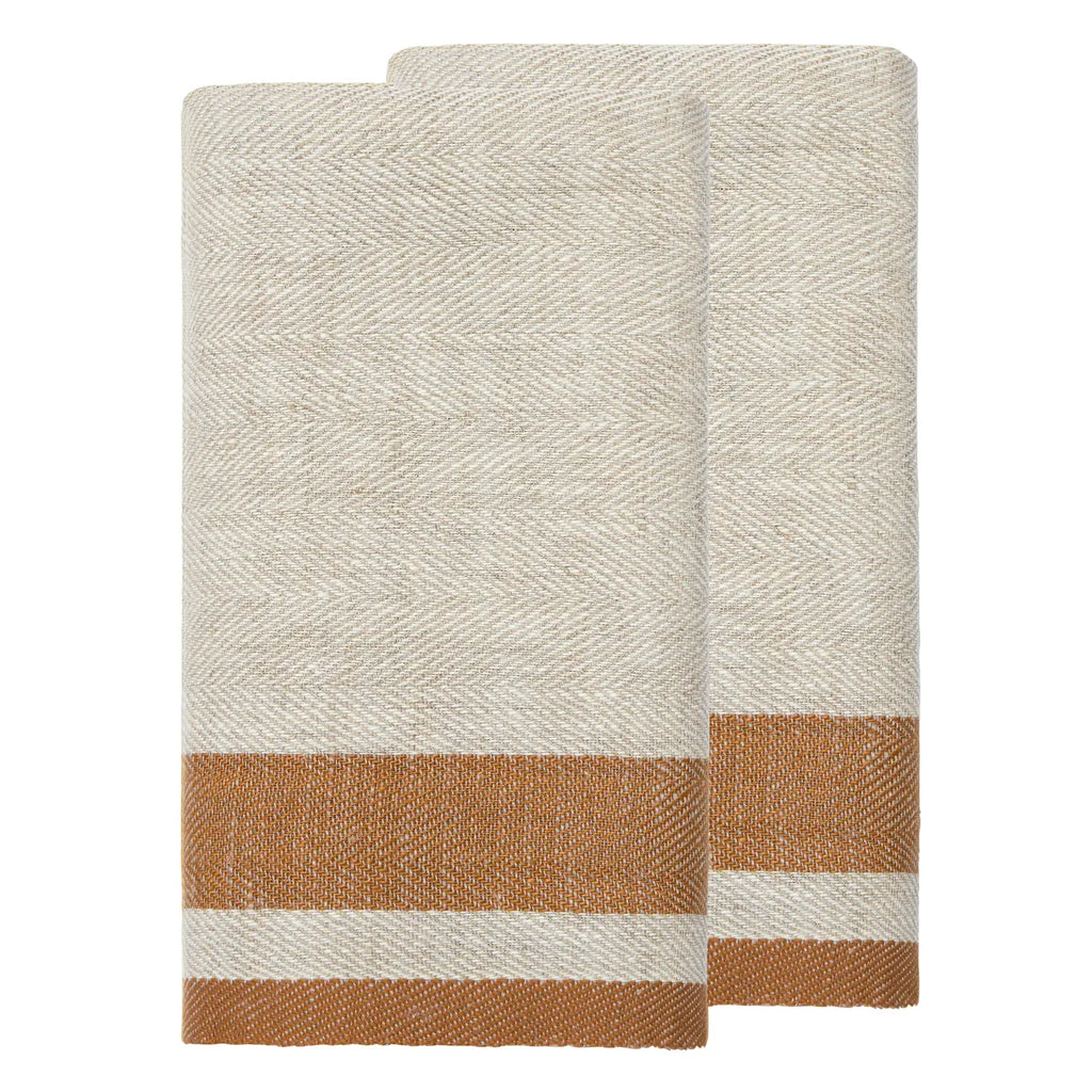 Two folded woven towels with a cream and tan herringbone pattern and a rust-brown striped border near the bottom, shown on a plain white background.
