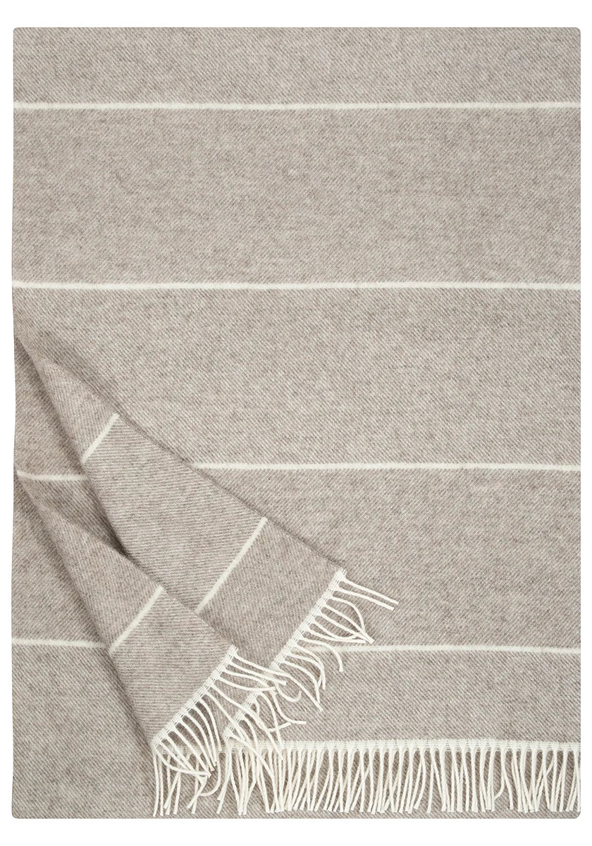 A light gray woven throw blanket with thin white horizontal stripes and fringed edges, shown folded on a white background.