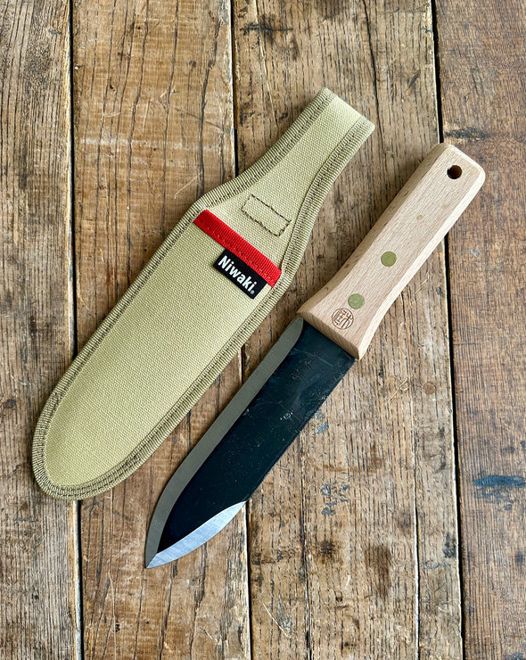 Knife with sheath on a wooden surface, featuring the Nivaki brand.
