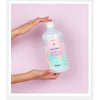 Person holding a bottle of Kerzon laundry detergent against a pink background