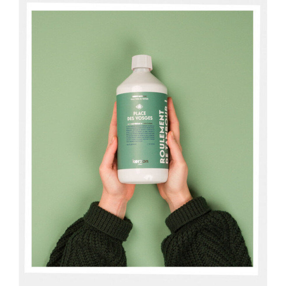 Person holding a green bottle of Kerzon laundry detergent with a white label against a green background