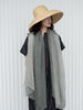Woman wearing a wide-brimmed hat and gray scarf against a white background