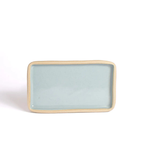 Rectangular ceramic plate with light blue glaze and beige rim on a white background