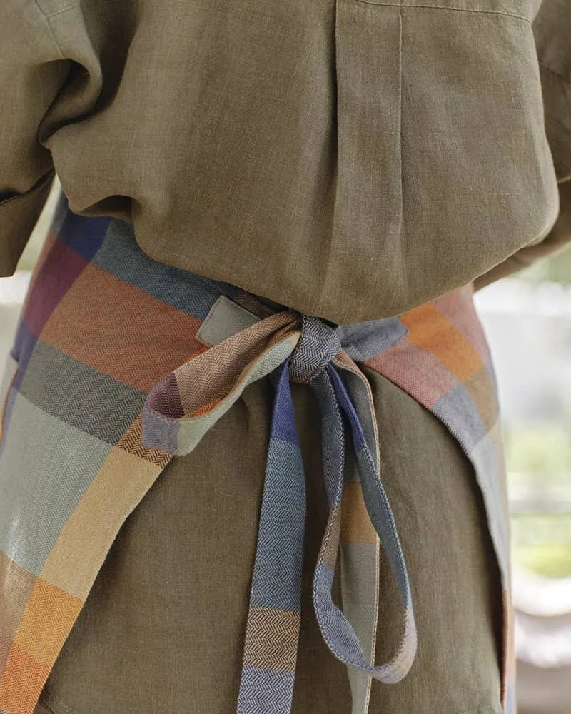 Person wearing a plaid apron with a blurred background