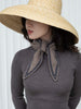 Woman wearing a wide-brimmed hat and a gray sweater with a scarf.